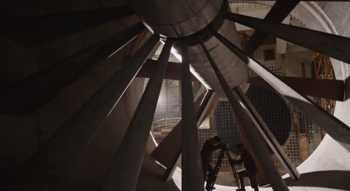 Large turbine with two people climbing ladders